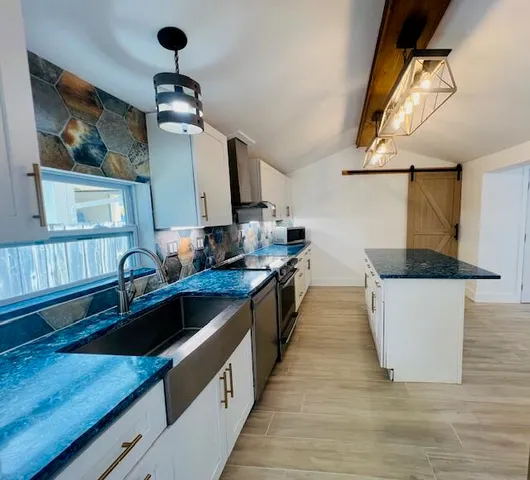 a kitchen with stainless steel appliances granite countertop a sink a stove and a wooden floors