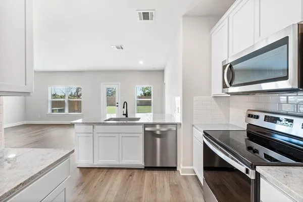 a kitchen with stainless steel appliances kitchen island granite countertop a stove a sink and a microwave