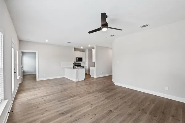 a view of empty room with wooden floor and ceiling fan