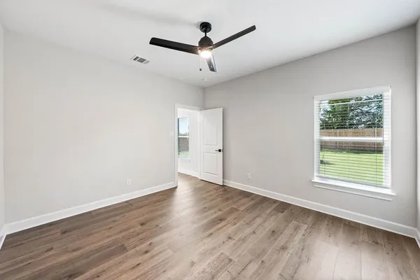 an empty room with wooden floor and windows