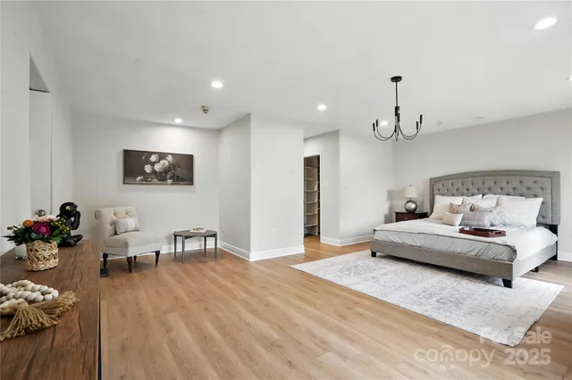 a spacious bedroom with a bed a couch and a dresser with wooden floor