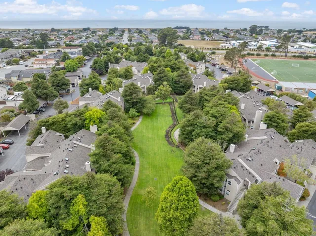an aerial view of a residential houses with outdoor space and trees