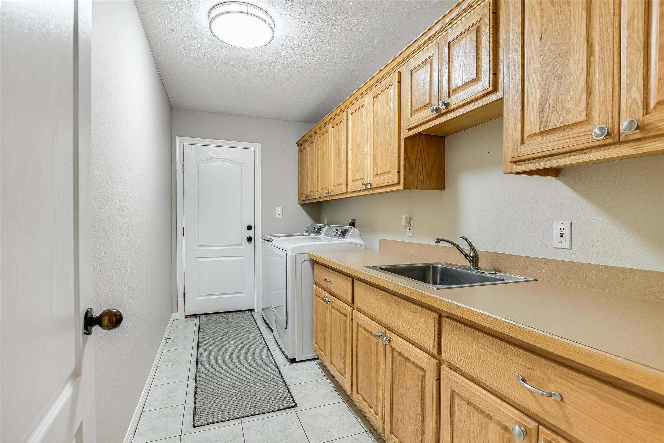 741 Knobbs Road McDade, TX 78650 - Photo 22 of 38 Functional laundry space featuring plentiful cabinetry, a convenient sink, and tiled flooring.