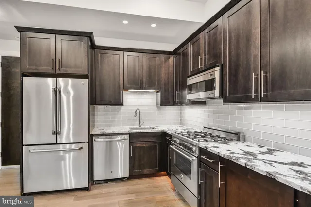 a kitchen with stainless steel appliances granite countertop a refrigerator stove microwave and sink