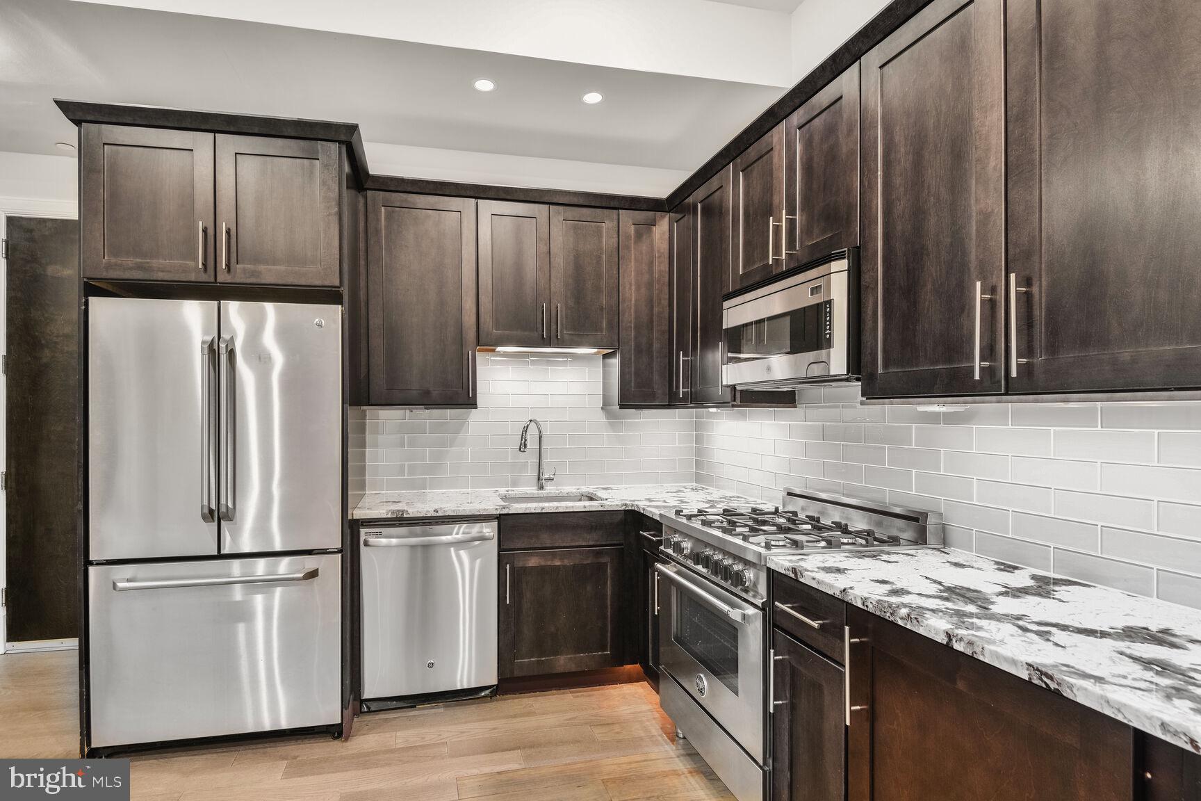 2009 Columbia Road Northwest, Unit 3 Washington, DC 20009 - Photo 4 of 16 a kitchen with stainless steel appliances granite countertop a refrigerator stove microwave and sink