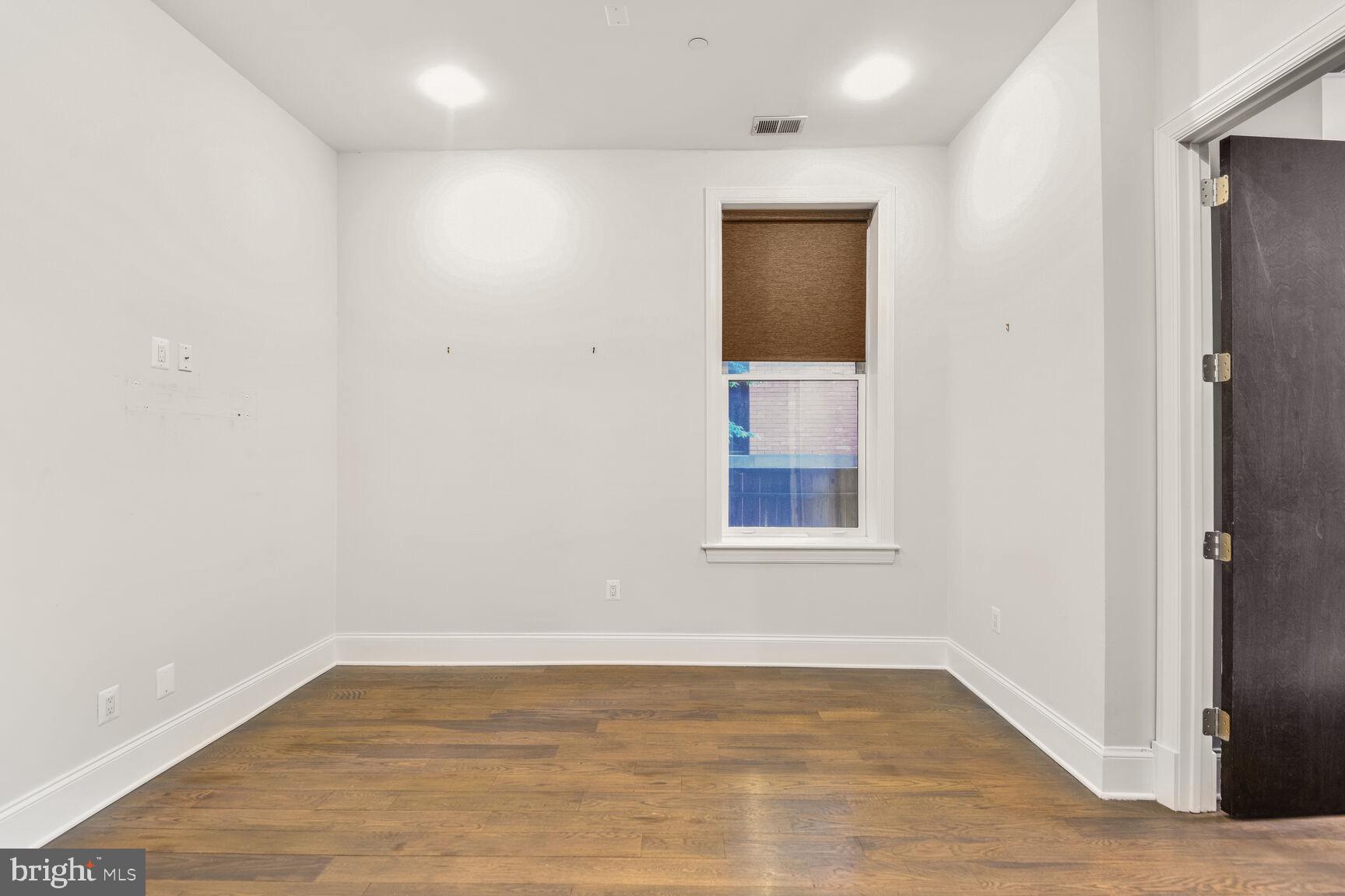 2009 Columbia Road Northwest, Unit 3 Washington, DC 20009 - Photo 7 of 16 an empty room with wooden floor and windows