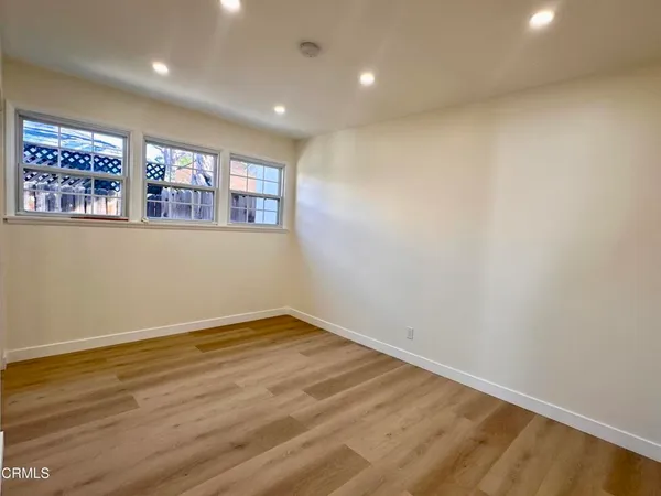 a view of an empty room with window and wooden floor