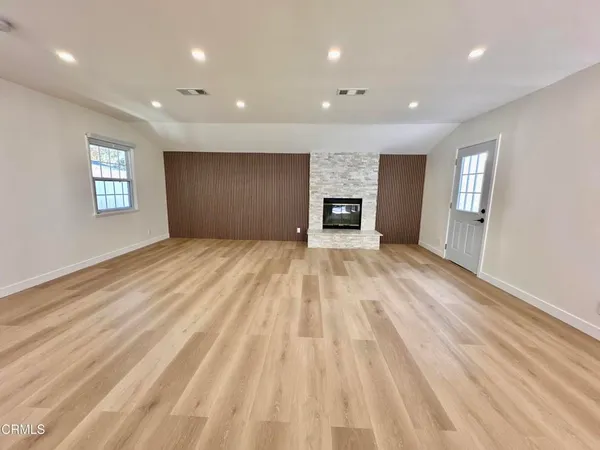 a view of empty room with wooden floor and fireplace
