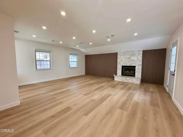 a view of empty room with wooden floor and fireplace