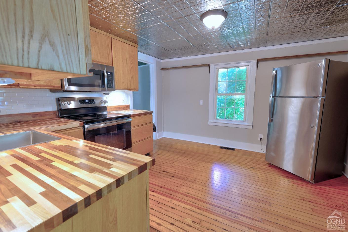 21 Irondale Road Millerton, NY 12546 - Photo 26 of 73 a kitchen with kitchen island a stove a refrigerator wooden floor and a view of living room