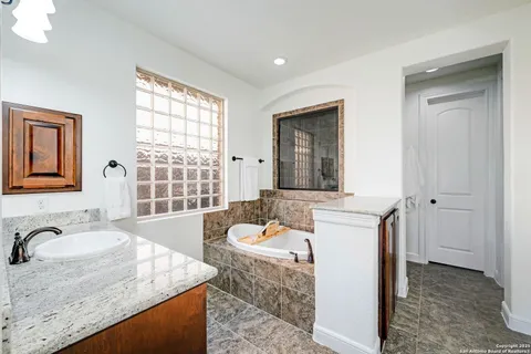 a bathroom with a granite countertop sink and a bathtub