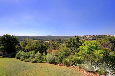 a view of a lush green outdoor space with a swimming pool and valleys in the background