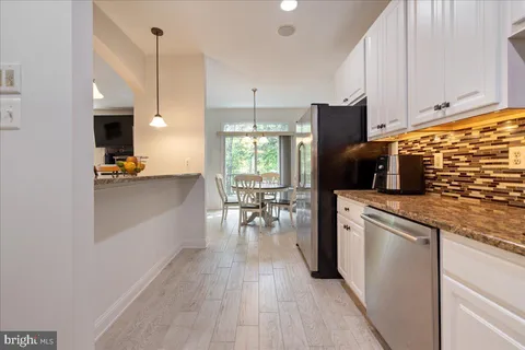 a kitchen with stainless steel appliances granite countertop a refrigerator a stove a microwave oven a dining table and chairs with wooden floor