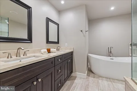 a spacious bathroom with a double vanity sink mirror and bathtub