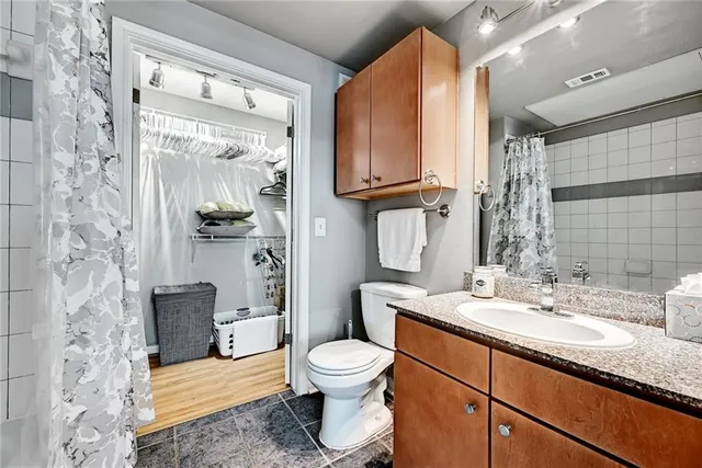 a bathroom with a granite countertop toilet a sink and a mirror