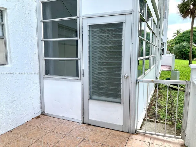 a view of a patio with table and chairs under an umbrella with palm trees