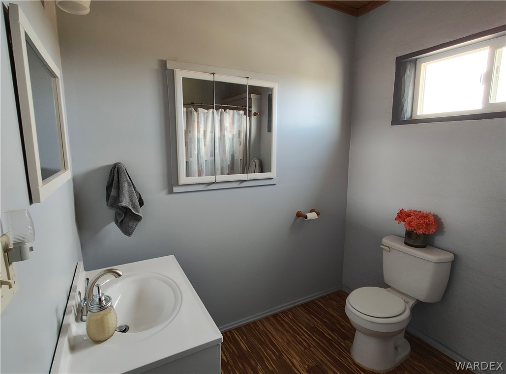 15 County Road Concho, AZ 85924 - Photo 13 of 93 Bathroom featuring a white vanity with a single basin sink, medicine cabinet with mirrored doors, a window with white trim, and wood-finish flooring