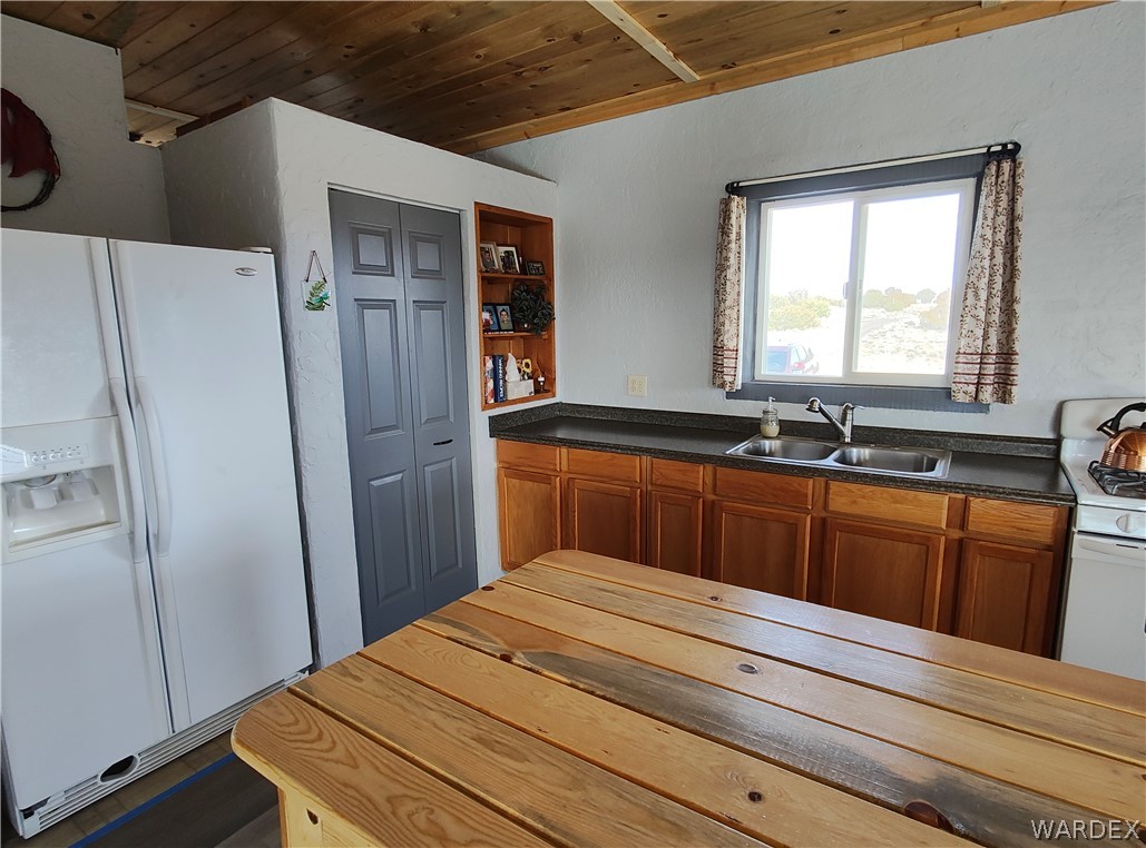 15 County Road Concho, AZ 85924 - Photo 19 of 93 Kitchen featuring wood-finish cabinetry, dark countertops, a double-basin stainless steel sink, and a wood plank ceiling