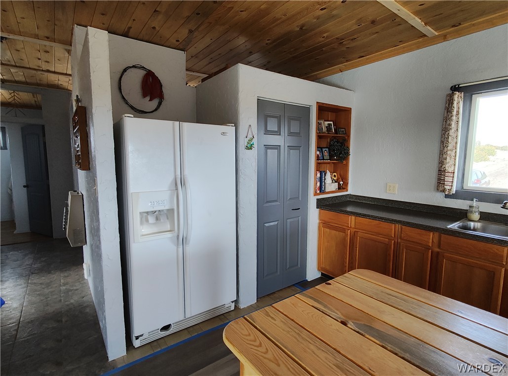 15 County Road Concho, AZ 85924 - Photo 20 of 93 Kitchen featuring a wood plank ceiling, built-in wooden cabinetry, dark countertops, and a stainless steel sink