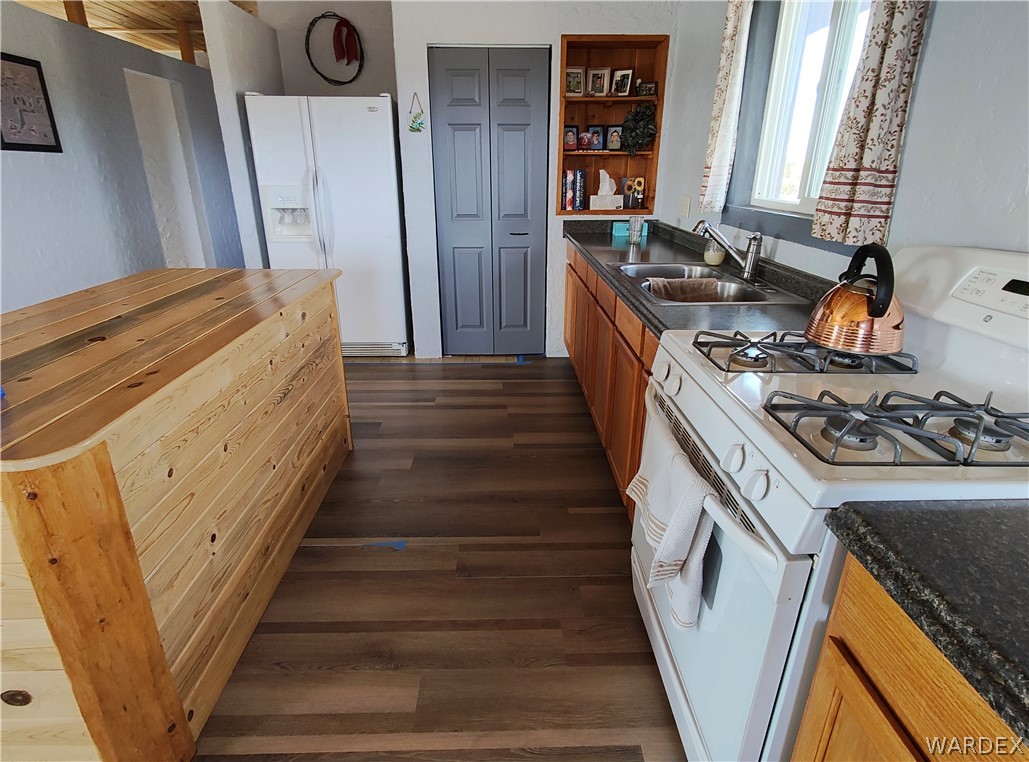 15 County Road Concho, AZ 85924 - Photo 23 of 93 Kitchen featuring wood-finish flooring, a built-in wooden island, wood cabinetry, dark countertops, and a double-basin stainless steel sink with a window above