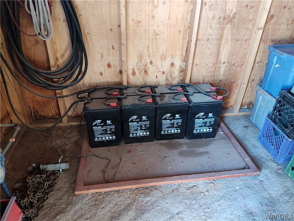 15 County Road Concho, AZ 85924 - Photo 34 of 93 Four industrial batteries with wired connections against a wood-paneled wall, set on a raised platform