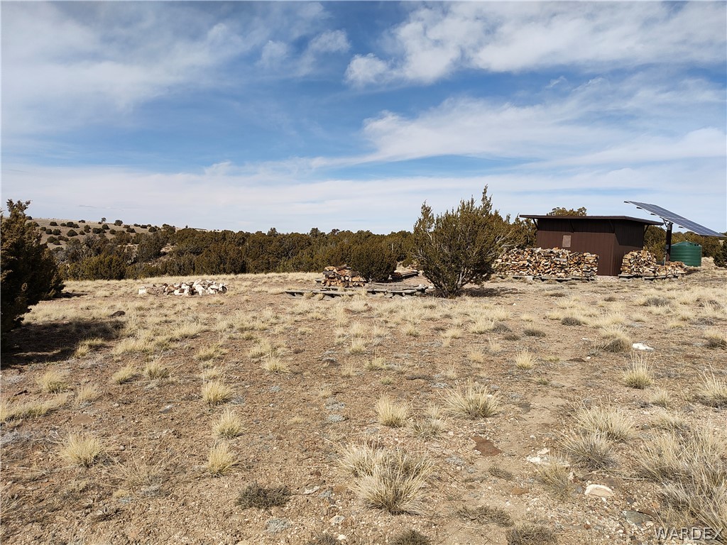 15 County Road Concho, AZ 85924 - Photo 49 of 93 Expansive landscape featuring a brown utility building with an attached solar panel array and a green water storage tank