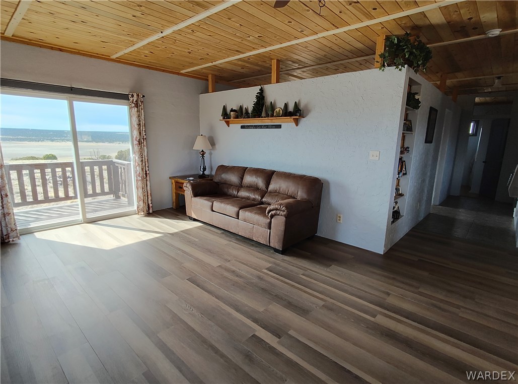 15 County Road Concho, AZ 85924 - Photo 72 of 93 Living area featuring wood-finish flooring, a wood-paneled ceiling, sliding glass doors to an outdoor deck, a partial wall with built-in shelving, and a hallway beyond