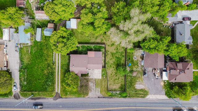 244 North 600 West Logan, UT 84321 - Photo 8 of 30 Aerial perspective showcasing a parcel with a brown-roofed structure, featuring a gravel driveway, mature trees, and extensive green space