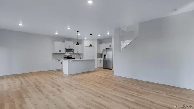 a view of kitchen with kitchen island wooden floor center island and stainless steel appliances
