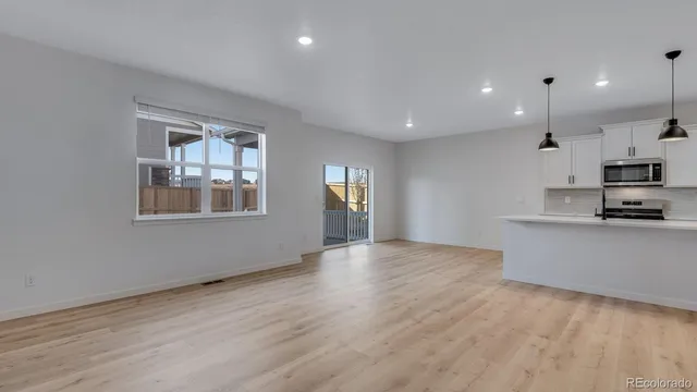 a view of empty room with kitchen and window