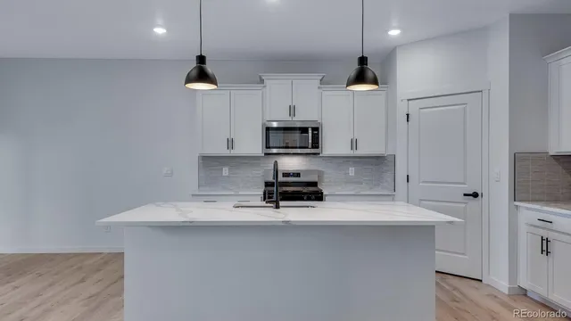 a kitchen with granite countertop a sink stainless steel appliances and white cabinets