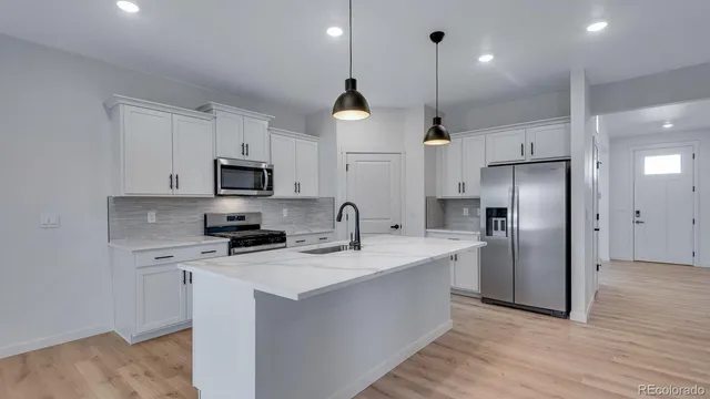 a kitchen with stainless steel appliances granite countertop a refrigerator a stove a sink dishwasher and a refrigerator with wooden floor