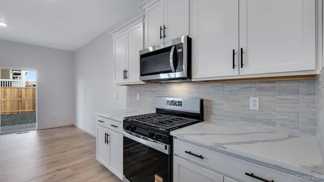 a kitchen with stainless steel appliances white cabinets and a stove top oven