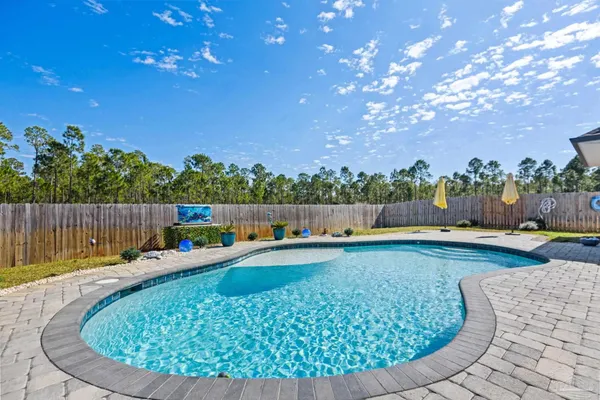 a view of swimming pool with seating space and trees in the background