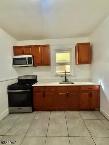 a large kitchen with granite countertop stainless steel appliances a stove sink and microwave