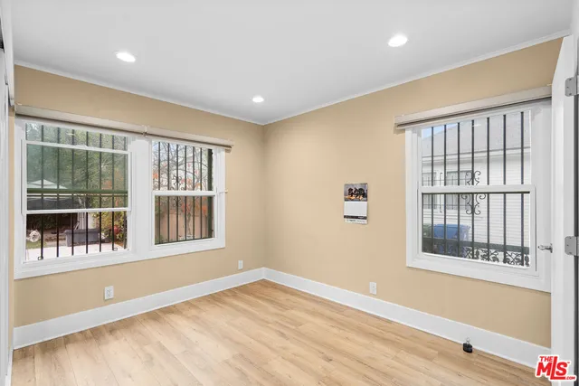 a view of an empty room with a window and wooden floor