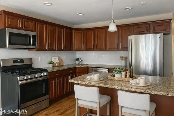 a kitchen with stainless steel appliances granite countertop a stove a sink dishwasher and a refrigerator with wooden cabinets