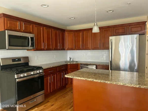 a kitchen with granite countertop a stove a sink and a microwave
