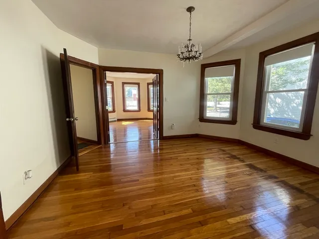 a view of an empty room with window and wooden floor