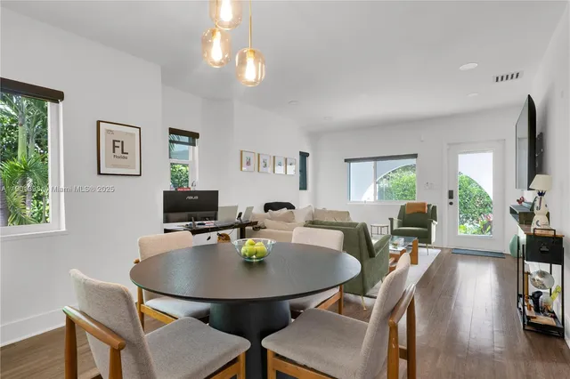 a dining room with furniture a potted plant a window and a flat screen tv