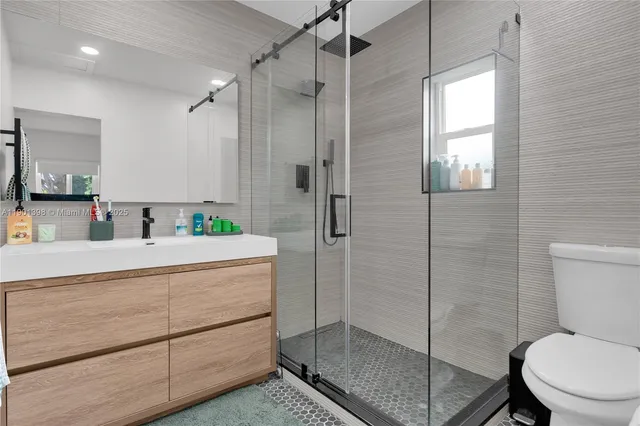 a bathroom with a shower sink mirror and toilet