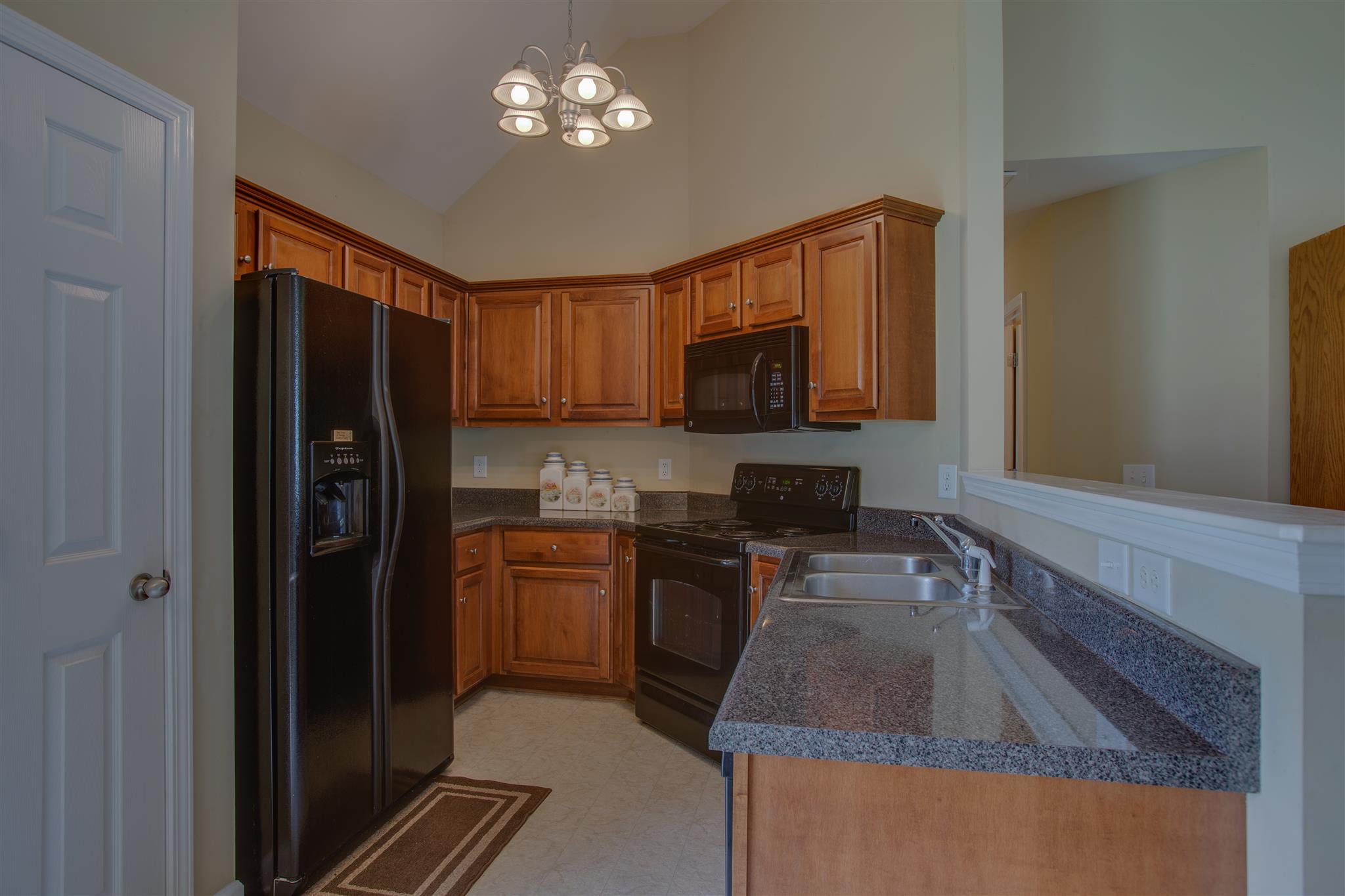 7039 Nickalus Way Spring Hill, TN 37174 - Photo 9 of 21 a kitchen with kitchen island granite countertop stainless steel appliances a sink stove refrigerator and microwave