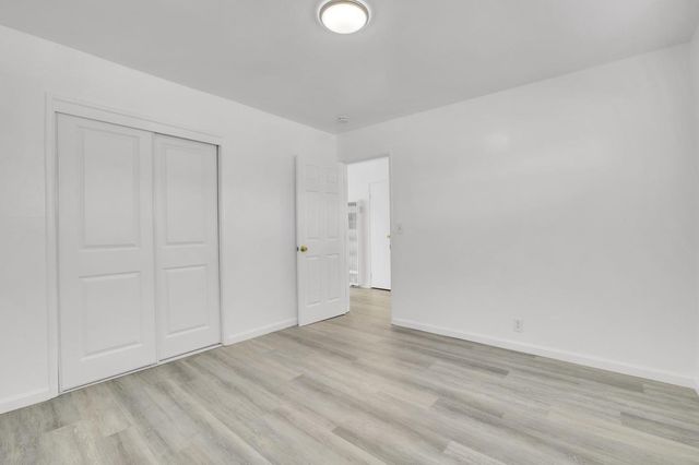 a view of an empty room with wooden floor and closet