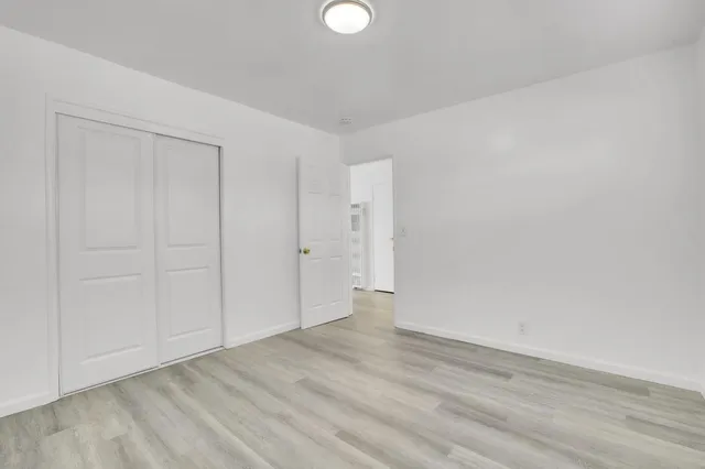 a view of an empty room with wooden floor and closet