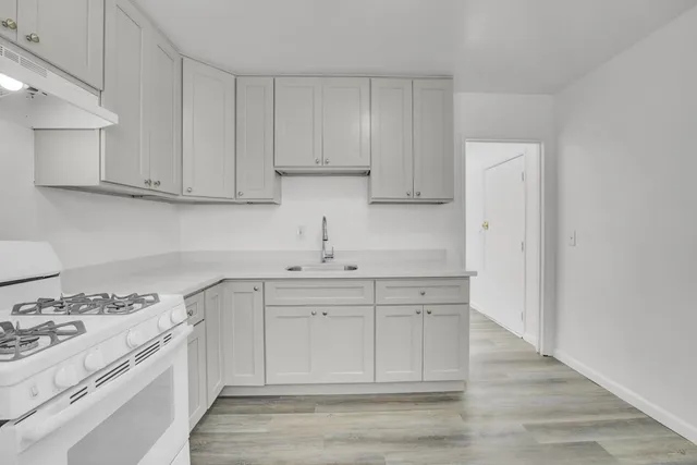 a kitchen with white cabinets and sink
