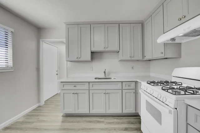 a kitchen with white cabinets and sink