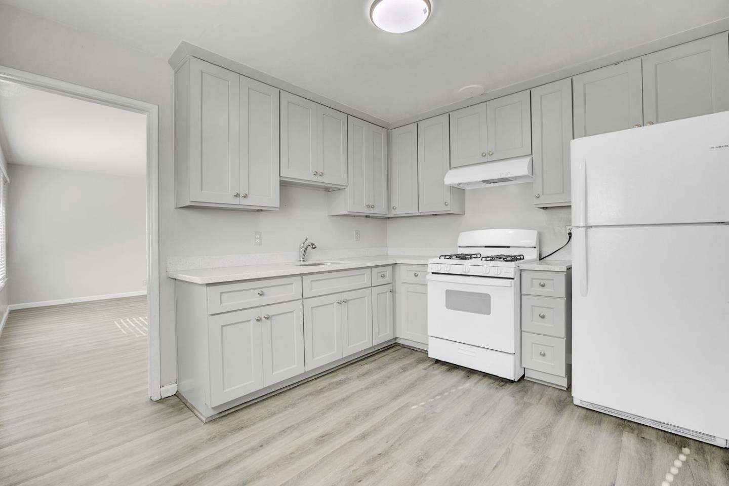 8811 A Street Oakland, CA 94621 - Photo 24 of 30 a kitchen with white cabinets white appliances and sink