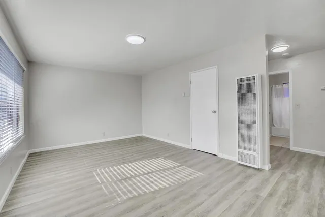 an empty room with wooden floor and windows