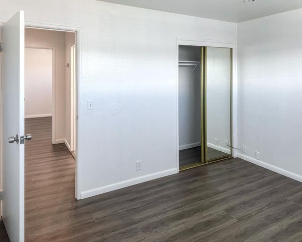 an empty room with wooden floor & closet area