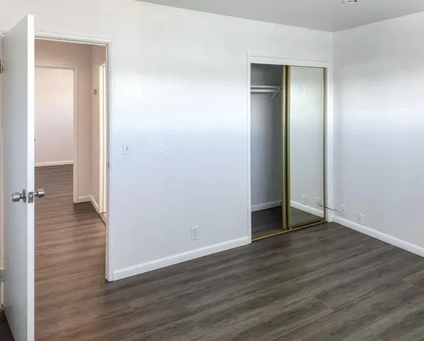 an empty room with wooden floor & closet area
